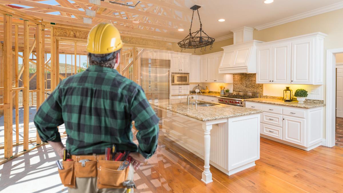 Kitchen remodeling contractor inspecting a modern kitchen under construction transitioning from framing to a finished design.