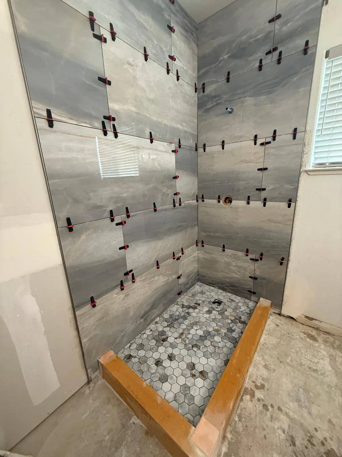 Modern bathroom shower installation featuring gray marble tiles and a hexag